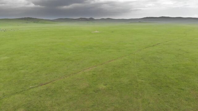 Stone kurgan and sacred stele stand on Mongolia steppe as ancient burial monument.