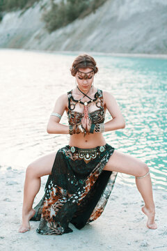 Beautiful girl in tribal fusion costume standing in a pose on the banks of the beach, background of blue sea.