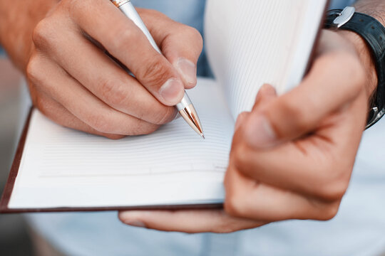 Man writing notes in a notebook. Hand holding pen
