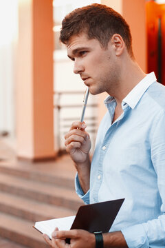 Young man with a notebook and pen thinking about work.