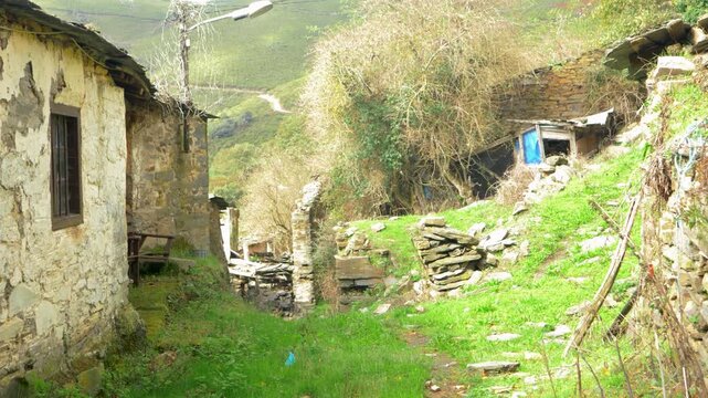 Old abandoned stone house surrounded by grass and vegetation in Santoalla do Monte, Galicia, Spain, capturing the quiet decay and rural depopulation of the remote settlement