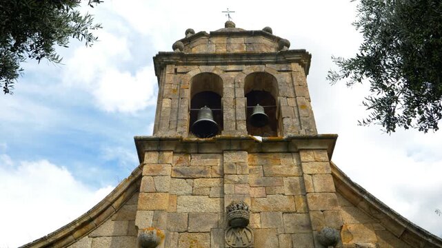 Upward view of the stone bell tower of Santa Mar&iacute;a de Mones Church in Pet&iacute;n, Ourense, Galicia, Spain, highlighting the historic religious architecture against the sky