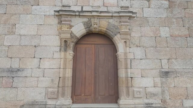 Close view of the traditional stone entrance and wooden door of the historic Church of San Miguel de Mones in Pet&iacute;n, Ourense, Galicia, Spain