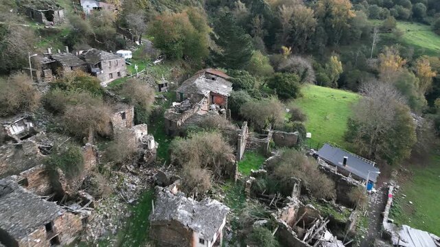 Aerial view over Santoalla do Monte in Galicia, Spain, showing stone houses, green fields and the small remote settlement surrounded by mountainous countryside