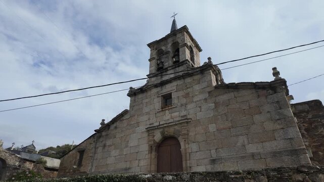 Front exterior view of San Miguel de Mones Church in Pet&iacute;n, Ourense, Galicia, Spain, featuring its traditional stone facade, wooden entrance and small bell tower.