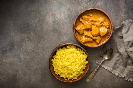 Traditional spicy Indian Chicken Tikka Masala with basmati rice on a dark grunge background, top view, flat lay.