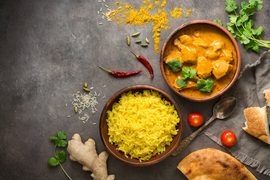 Traditional spicy Indian Chicken Tikka Masala with basmati rice on a dark grunge background, top view, flat lay.