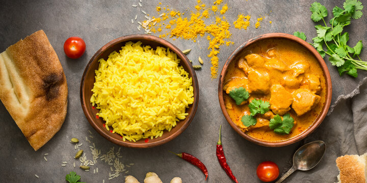 Traditional spicy Indian Chicken Tikka Masala with basmati rice on a dark grunge background, top view, flat lay.