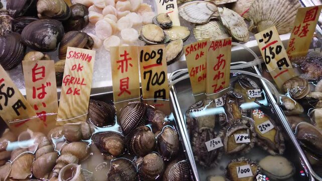 Close Up of Japanese Shellfish and Abalone with Handwritten Yen Prices at Traditional Seafood Market