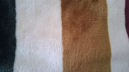 Close up of soft plush blanket fabric with striped color pattern and fuzzy textile texture © KarinFi