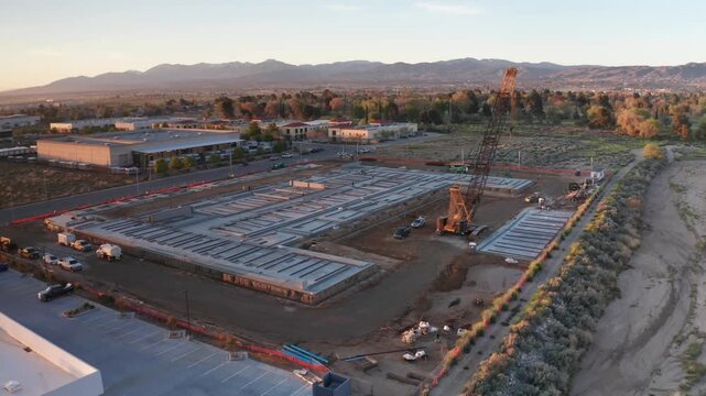 Aerial low panning shot of foundation work going on at a desert construction site during early morning in Palmdale, California. 4K