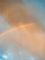 Obraz premium Faint Rainbow Beneath Dramatic Storm Clouds After Rain at Sunrise