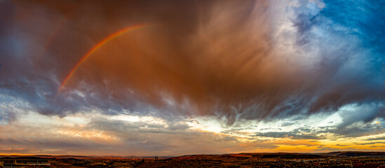 Obraz premium Panoramic Rainbow and Dramatic Storm Clouds at Sunrise After Rain