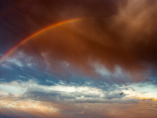 Obraz premium Faint Rainbow Beneath Dramatic Storm Clouds After Rain at Sunrise