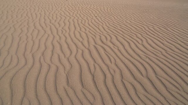 Close view of desert sand ripples and dune patterns across a barren empty landscape.