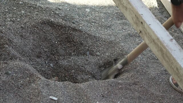 Ground excavation digging deep holes for fence posts in a garden using a manual spade. High-angle static close-up shot.