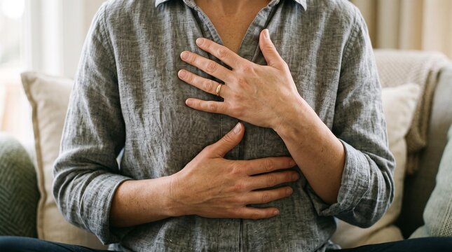 Woman with hands on chest experiencing acute pain or discomfort. Image symbolizes potential heart attack, anxiety, or stress, needing medical attention