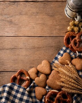 Oktoberfest background with gingerbread hearts pretzels and wheat on wood.