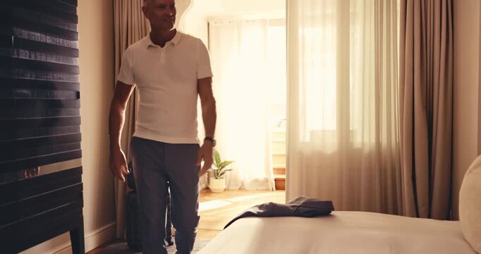 Luggage, man and arrival in hotel room with relax, overnight stay and unwind for business travel. Suitcase, mature professional or smile on bed for work trip checkin, traveler downtime or hospitality