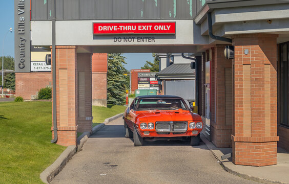 Calgary, AB, Canada - Sept 14, 2026: Classic orange muscle car exiting a drive-thru lane marked with a red exit only sign.