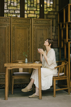 Beautiful young woman drinking jasmin tea sitting in a traditional chinese tea house.