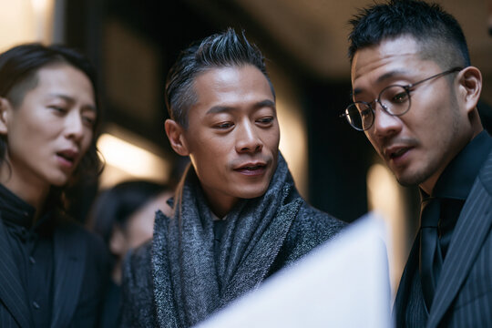 Asian Businessmen Reviewing Documents During Strategic Meeting