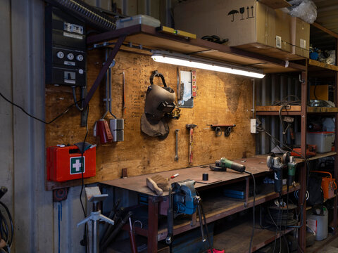 A well used container workshop with distribution board, first aid kit and a plywood tool wall above a steel workbench.