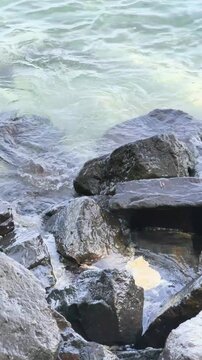 Large coastal rocks washed by clear sea water waves