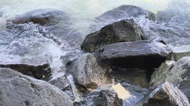 Crashing sea waves creating white foam on breakwater rocks