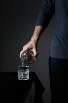 Man pouring strong alcoholic drink in glass.