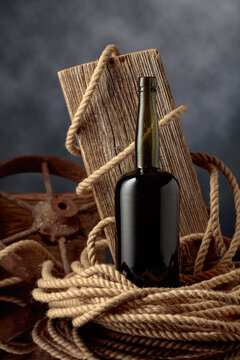 Antique bottle of alcoholic beverage against the backdrop of an old weathered board and hemp rope.