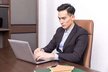 Fototapeta premium Focused Asian Businessman Working on Laptop in Modern Office