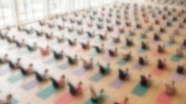 Blurred crowd of people doing a synchronized group workout in a large bright hall