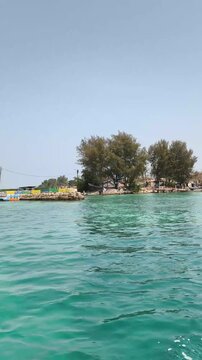 Clear turquoise sea water with lush green island in the background