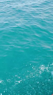 Clear blue ocean water surface with white splash foam