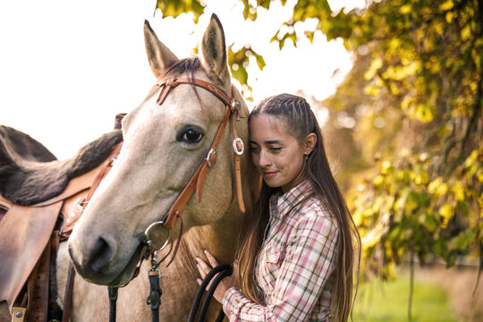Woman standing close to her horse. Connection between people and animal. Female rancher bonding with horse on pasture