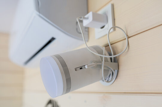 A wall-mounted projector hangs on the wall next to the air conditioner in the meeting room. Portable home theater. closed lid