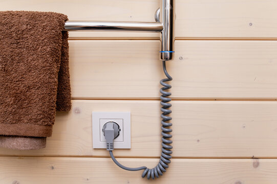 An electric towel warmer mounted on a wood-clad bathroom wall. Home coziness and comfort.