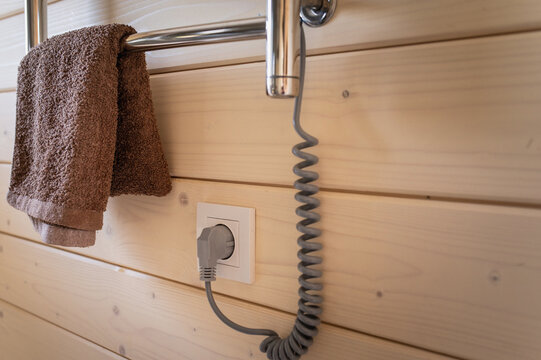 An electric towel warmer mounted on a wood-clad bathroom wall. Home coziness and comfort.