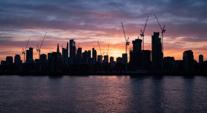 Skyline cityscape construction cranes vibrant dawn skyline urban development modern architecture waterfront silhouette