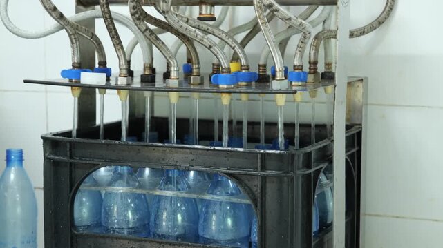 Water Bottling Factory Production Line with Bottled Water in Crates, Close-up of Water Bottles Being Filled in Factory Production Line	