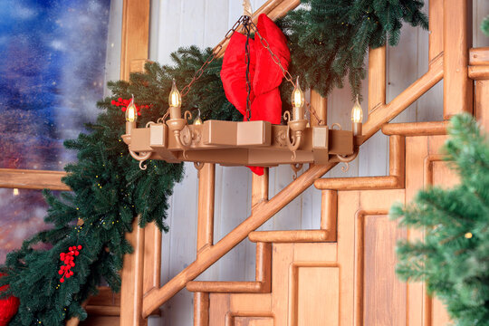 Festive Christmas chandelier adorned with greenery and a red bow hangs near stairs