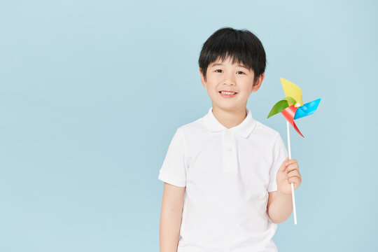 Happy boy holding a colorful toy pinwheel in studio
