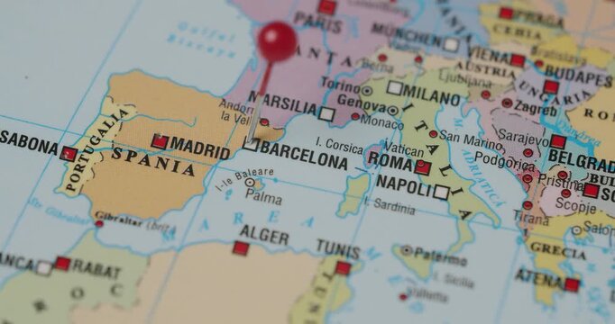 Close-up of a person's hand pinning the city of Barcelona on a political map of Europe, marking a travel destination, a specific location for a trip, or a point of interest for future travel