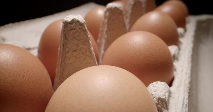 Cinematic push-in over cardboard package containing eggs, filmed with a probe lens. The close-up perspective highlights the natural texture of the eggs, creating a visual suitable for food production