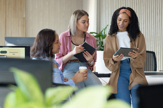 African American women in business casual meeting at office, holding tablet notebook pen and coffee