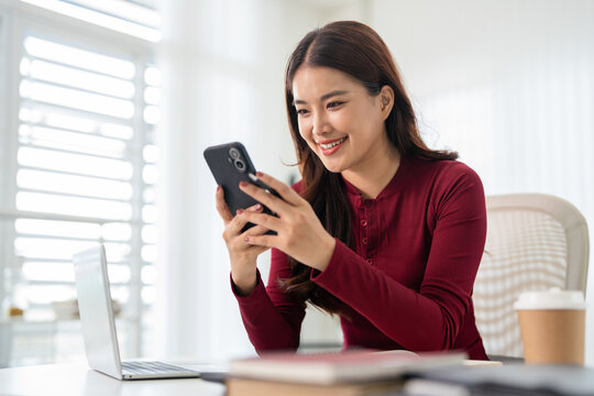 Young woman types on mobile device, sending emails and using technology for communication.