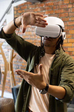 African American man wearing white VR headset, olive overshirt, gesturing with hands in loft studio