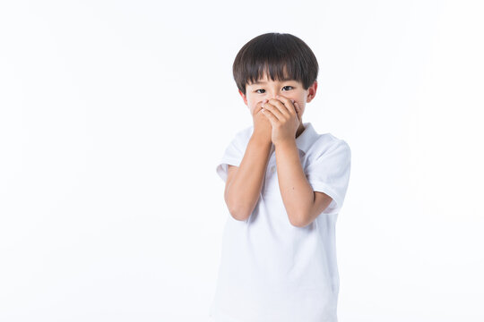 Surprised young Asian boy covering his mouth with hands in shock