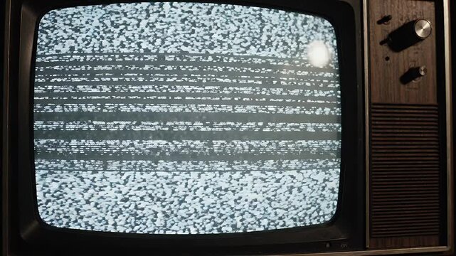 Vintage Television Static Screen - Close-up of a vintage television screen displaying static noise with horizontal lines. The wooden-cased television has visible knobs and a speaker grille.